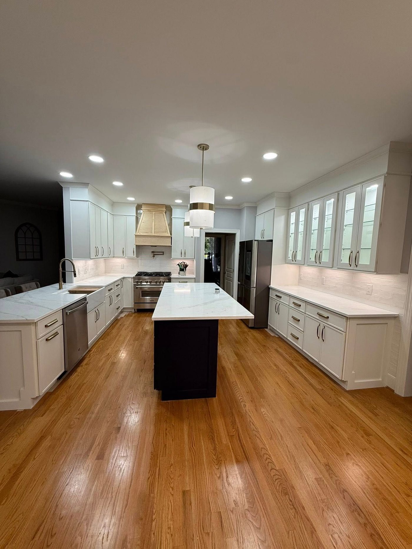 The same kitchen after: white cabinetry, marble-look counters, dark island