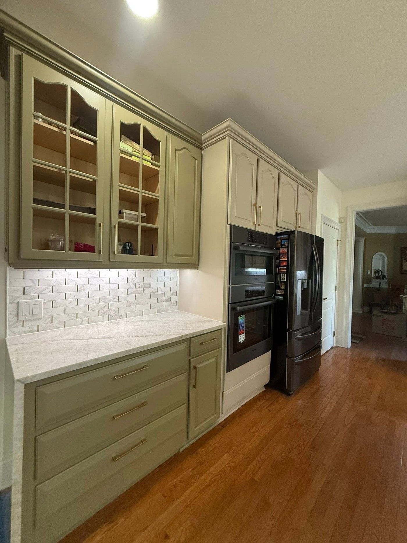 The same run refinished in sage green with glass uppers and a tile backsplash