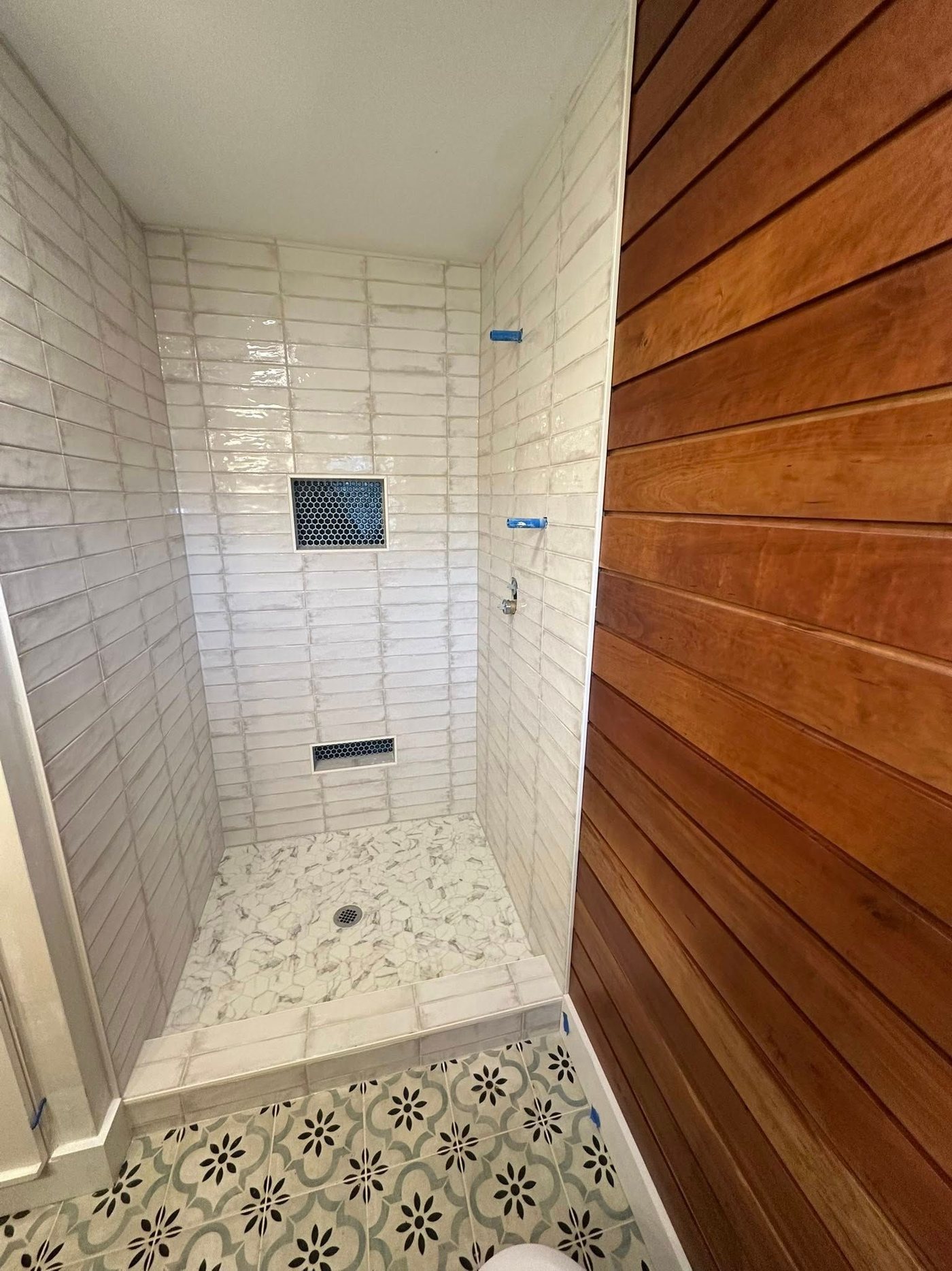 Walk-in shower with subway tile and wood-look feature wall
